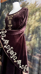 Golden ornamental trim along the sleeve of the brown velvet gown