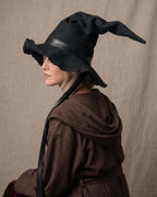 Side view of the black witch hat worn over a brown robe