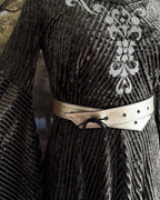 Cream belt tied at the waist of a striped velvet dress