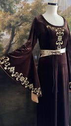 Side view of the brown velvet dress with gold sleeve trim